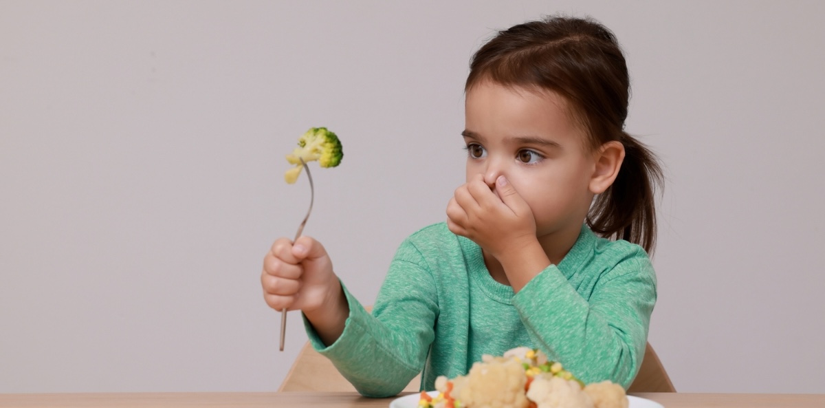 Girl holds her nose as she eyes a stalk of broccoli. This represents the question of whether nonprofit work is the right choice for you.