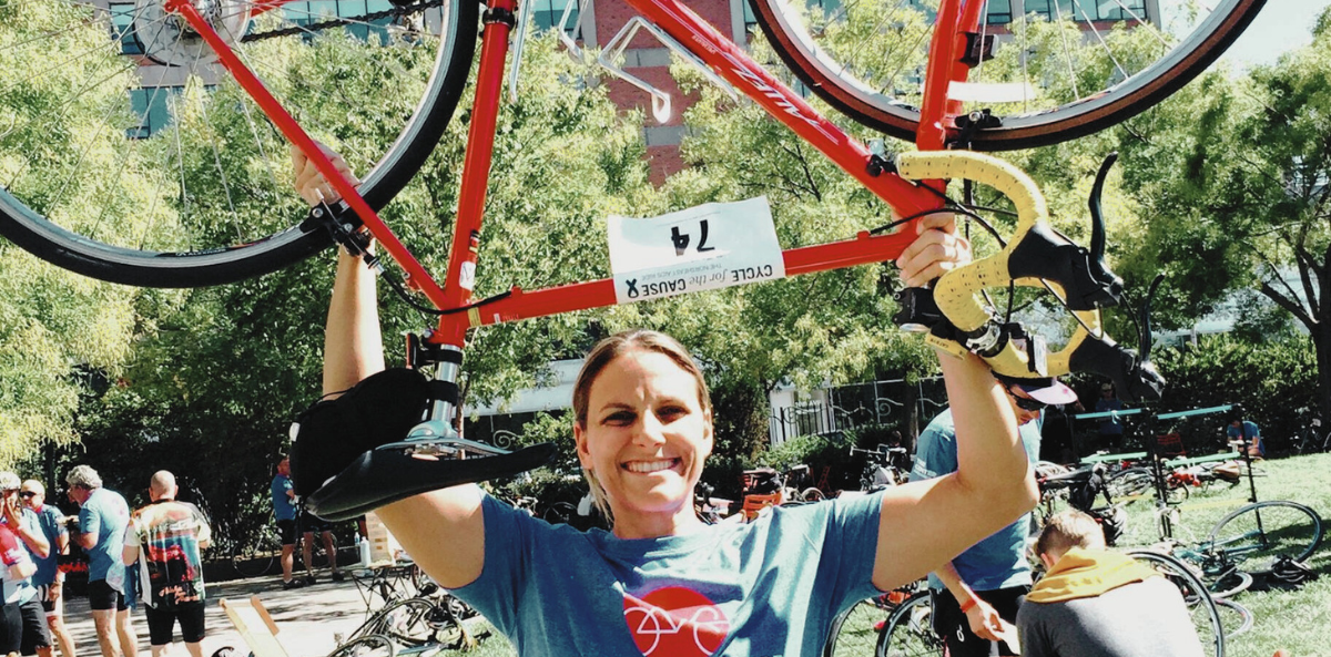 Glennda Testone holds up her red bicycle on a sunny day during a Cycle for the Cause event.