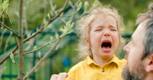 A young child cries in the arms of her dad.
