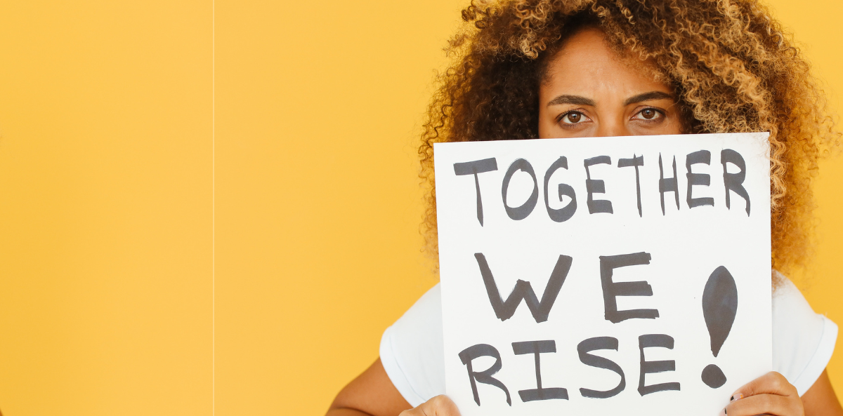 A person holds up a sign that says "Together we rise."