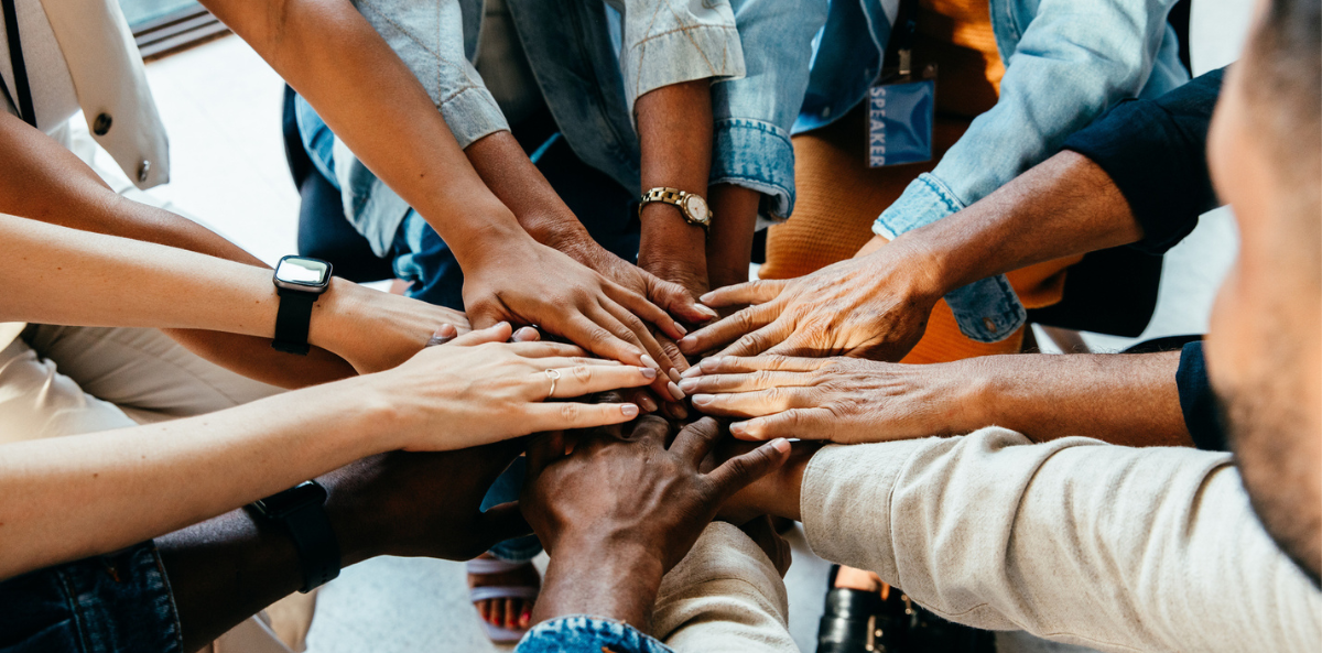 A group of diverse hands come together to form a cirle.