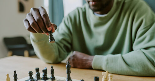 A man thoughtfully moving a chess piece, symbolizing strategic decision-making and leadership planning.