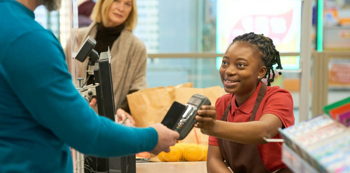 Cashier explaining a checkout donation option to a customer, highlighting how staff communication influences fundraising participation.