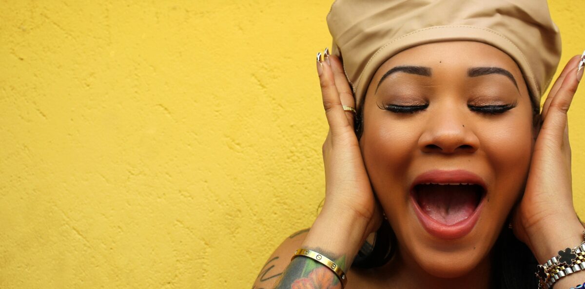 A woman covers her ears with both hands, mouth open in exasperation – capturing the frustration board members feel when one person dominates every meeting.